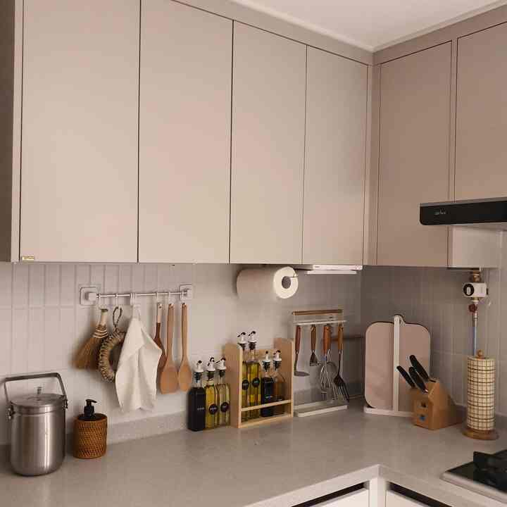 白と木目調が調和したシンプルで清潔感のあるキッチン、調理器具や収納アイテムが整然と配置されている