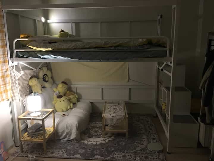 Beige and white toned small bedroom featuring a bunk bed, sofa bed, and storage shelves creating a cozy atmosphere