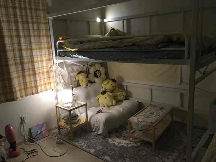 Yellow-toned small bedroom featuring a bunk bed, compact sofa bed, curtains, and character plush toys creating a cozy atmosphere