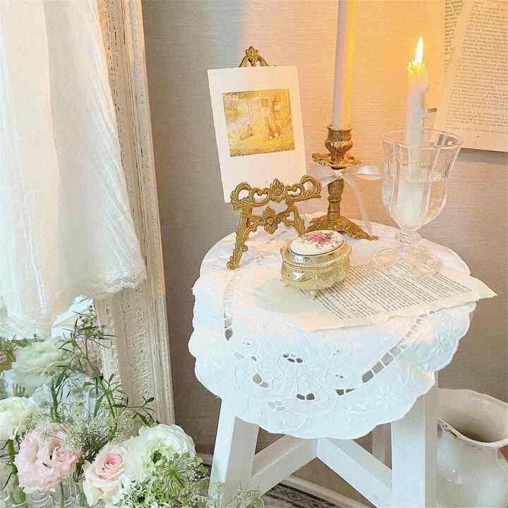 Vintage style cozy interior featuring white and gold toned table decor with candles and flowers