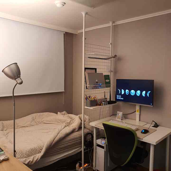 Beige-toned small room featuring white desk, bed, and a room divider creating a cozy home office atmosphere