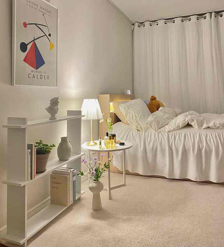 ホワイトトーンの寝室、ベッドと棚、ナイトテーブルと花瓶が配置された落ち着いたシンプルなインテリア