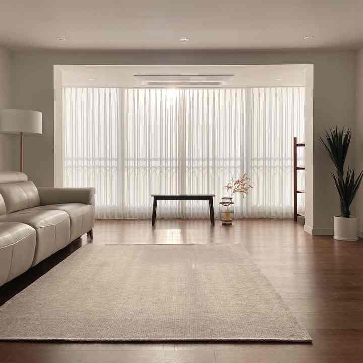 A cozy living room with white and wood tones, featuring a cream recliner sofa and sheer chiffon curtains