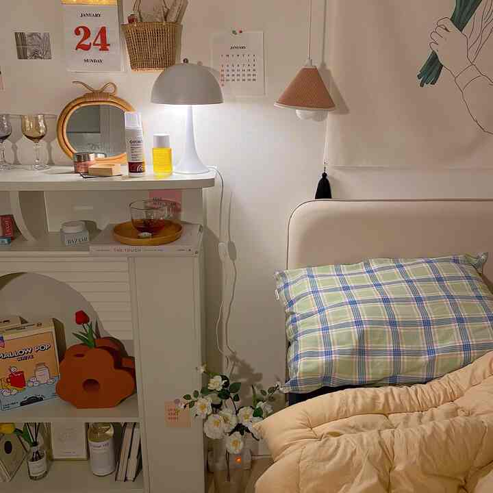 ホワイトとナチュラルトーンの6畳の寝室、ベージュの布団とチェック柄の枕が配置された雰囲気のある空間