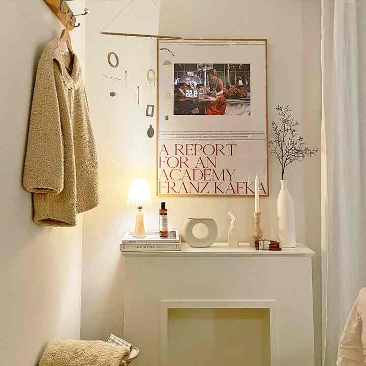 White and wood-toned fireplace console space featuring candles, vases, and a coat rack arranged in a cozy simple interior