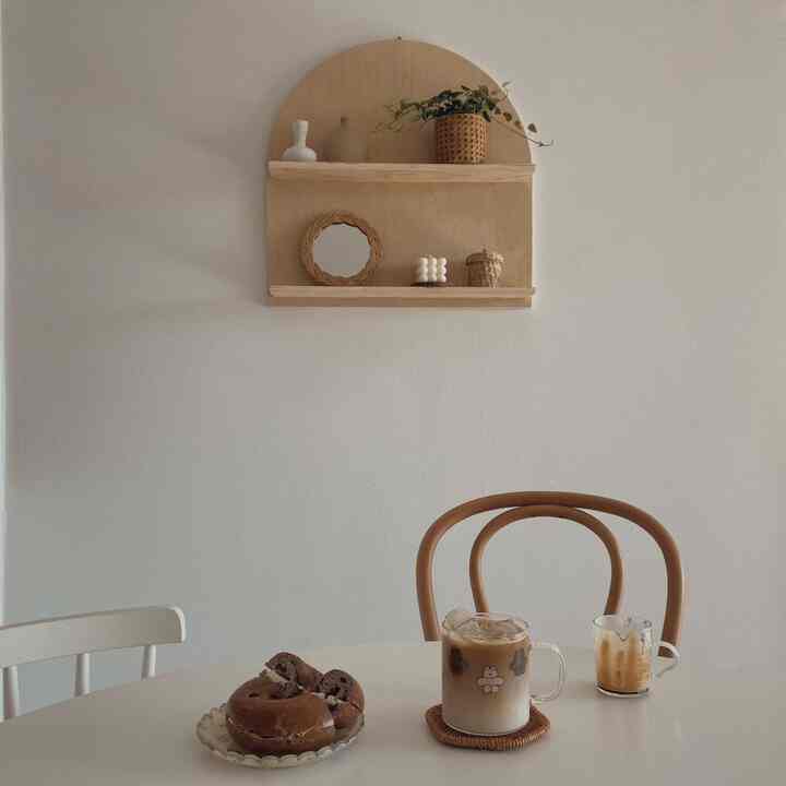 Cozy kitchen space with natural-toned dining table and arch-shaped wall shelf