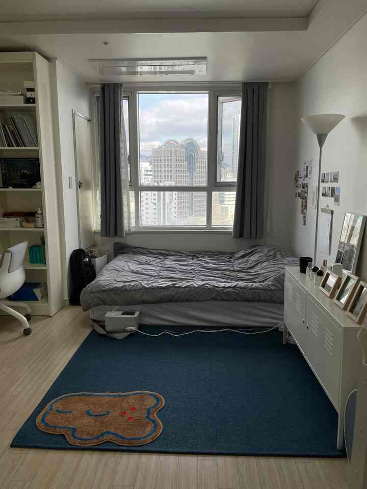 Natural tones with white walls and wood flooring in a single bedroom featuring a bed, desk, and city view through large window