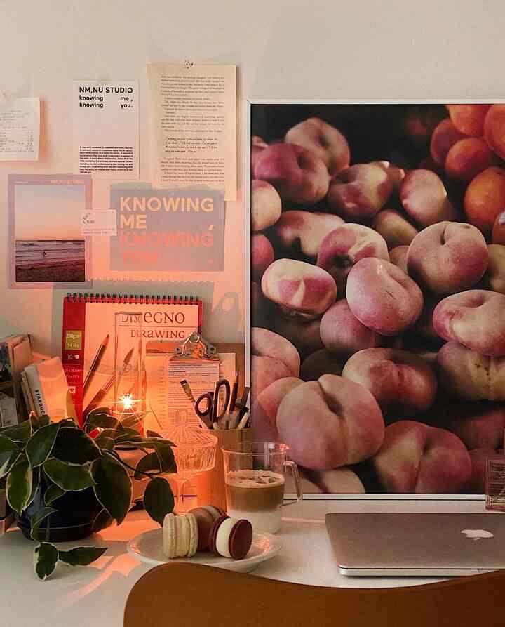 Warm natural-toned home office featuring a large fruit poster, macarons, and coffee creating a cozy vibe