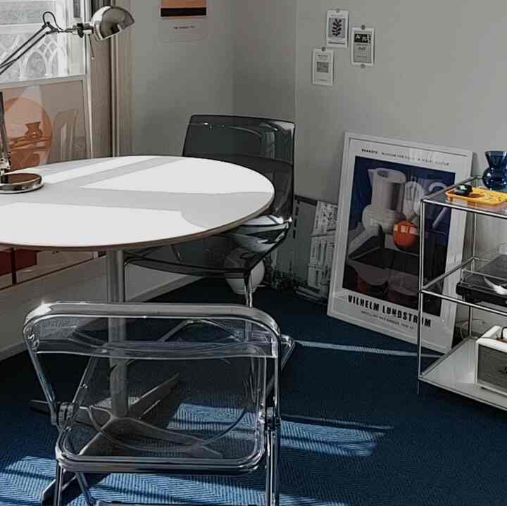 ホワイトとネイビーカラーのカフェ風の空間、透明な椅子と円形テーブルが配置されたモダンで落ち着いたインテリア