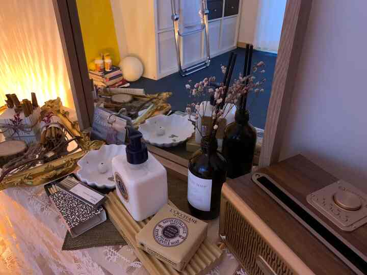 A white and gold-toned vanity space featuring a wooden tray with a diffuser set, wood tones creating a cozy, natural atmosphere