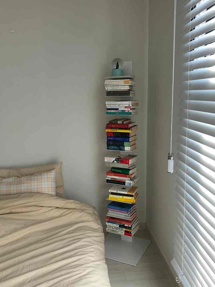 White and beige toned bedroom featuring a bedside bookshelf in a cozy corner