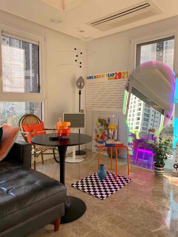 Black and orange toned living room featuring a black leather sofa, round table, rattan armchair, and mobile decor creating a cozy atmosphere