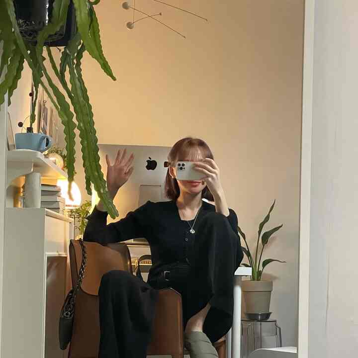 暖かいベージュトーンのワンルーム、茶色のアームチェアと透明なスツール、植物が配置されたナチュラルモダンなホームオフィスとおうちカフェの空間