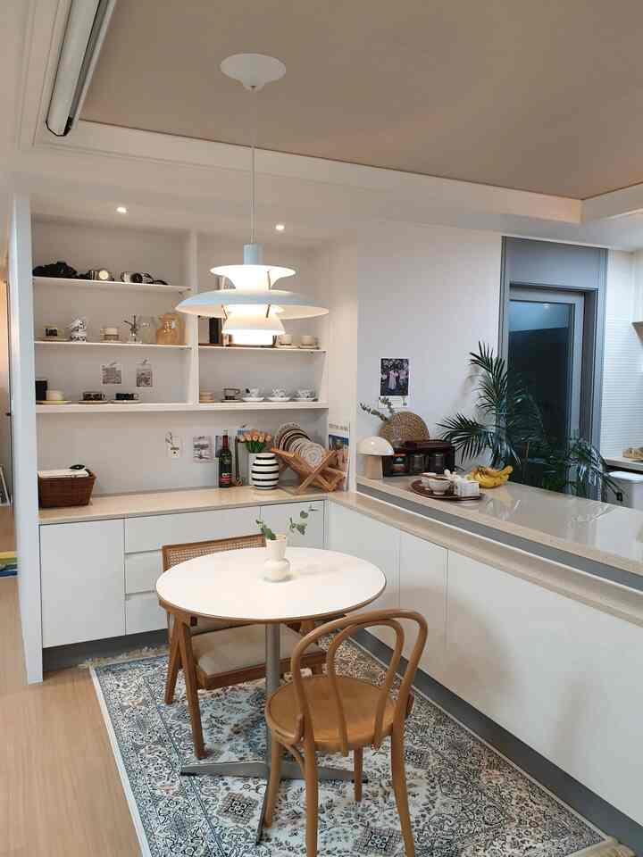 白と木目調が調和するカフェ風ダイニング、ラタンチェアとペンダントライトが配置された雰囲気のある空間