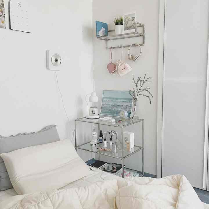 White and gray toned bedroom featuring modern style with bed, nightstand, and shelves arranged in a cozy space