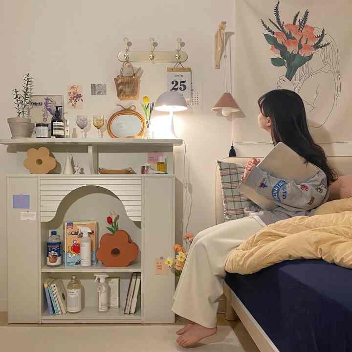 Natural modern bedroom in white and navy tones, featuring a bed, shelving unit, and cozy lighting