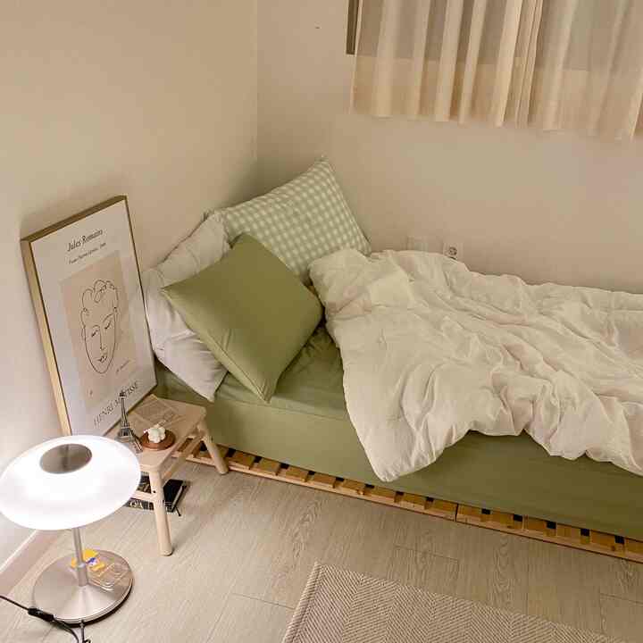 Natural-toned bedroom with light green bedding and wooden bed frame creating a cozy atmosphere