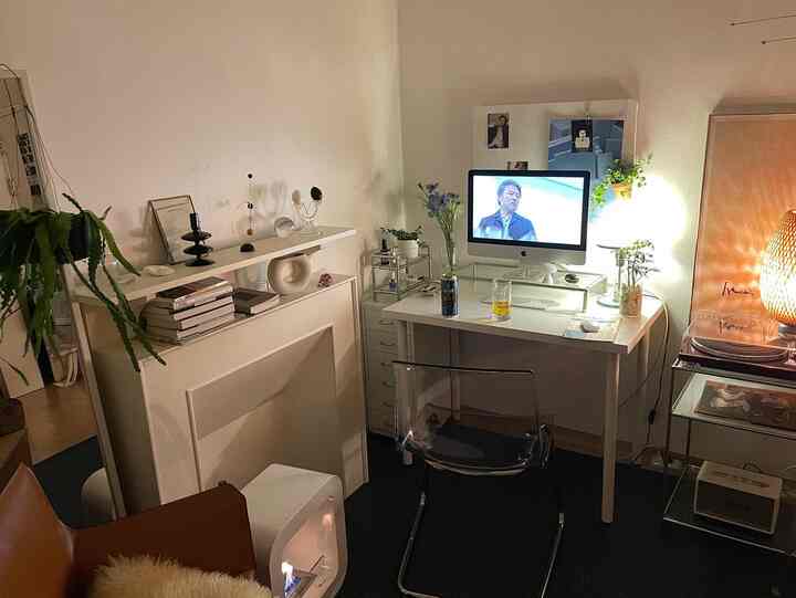White-toned home office featuring a transparent chair and computer desk, creating a modern indoor atmosphere