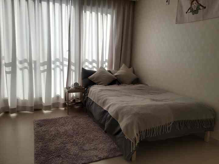 Beige and light brown toned bedroom featuring a bed and blackout curtains for a cozy atmosphere