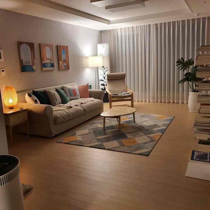 Cozy living room featuring warm wood tones with beige sofa, armchair, and patterned rug, illuminated by warm lamps