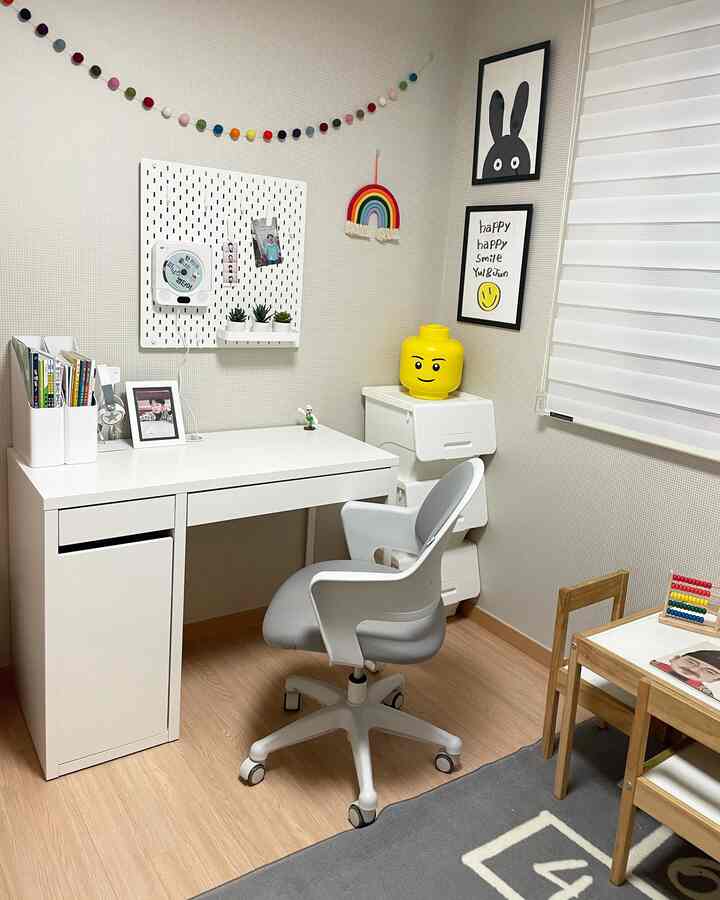 Bright and tidy kids' room with white walls and wood-toned floor, featuring a desk, ergonomic chair, and storage units arranged neatly