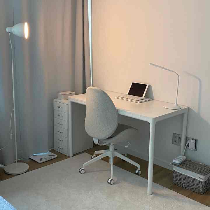 白を基調としたホームオフィス、シンプルな机と椅子、フロアランプが配された清潔感のあるインテリア