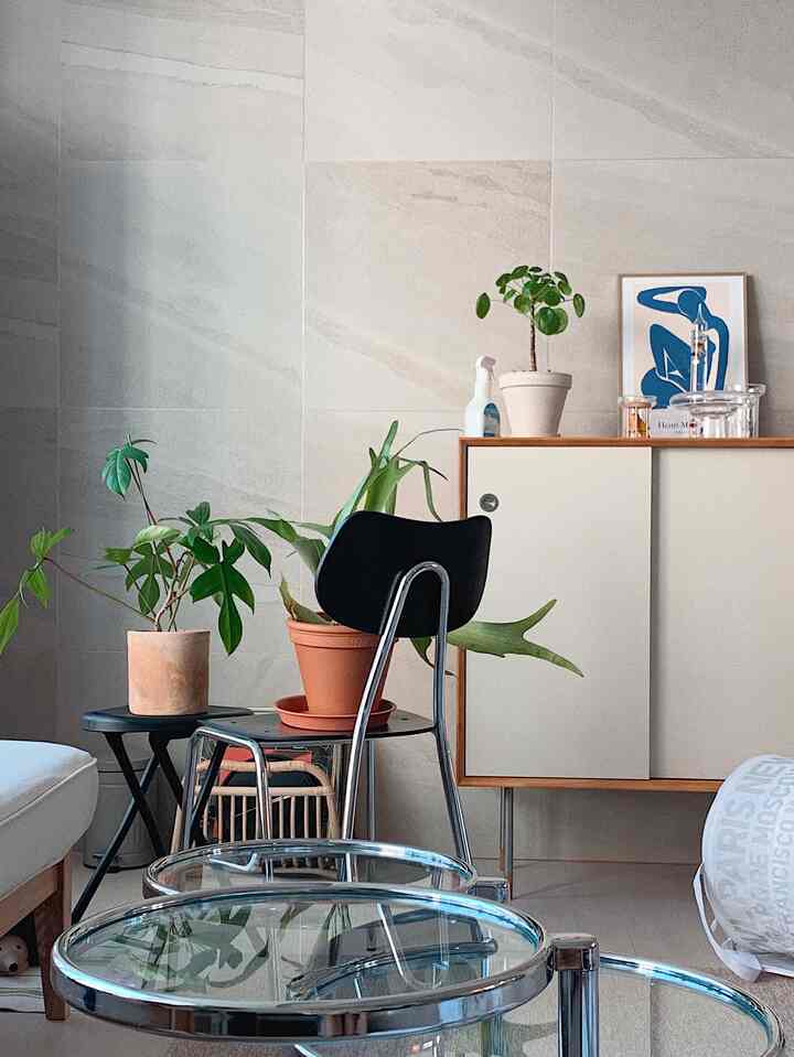 White and brown toned living room featuring Arno Chair, transparent glass coffee tables, and plants in a modern natural setting