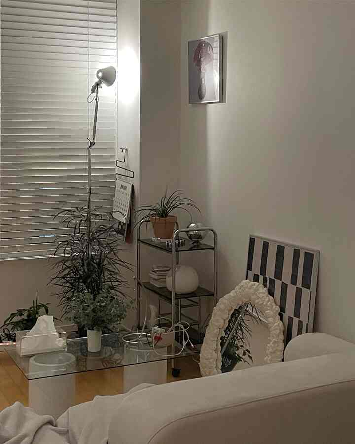 白とナチュラルカラーのリビングルーム、植物とシンプルなフロアランプを配した落ち着きのあるインテリア
