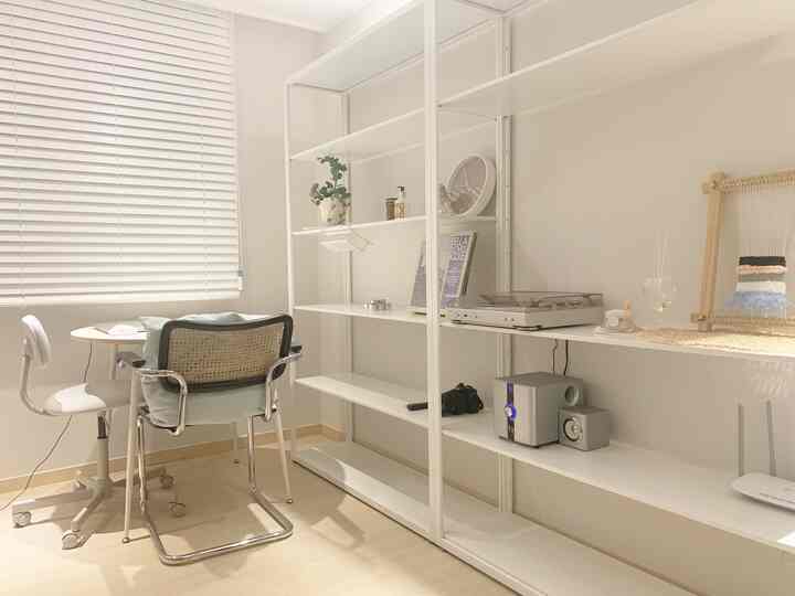 Bright white and light brown toned home office space featuring desks and chairs near a window with blinds, organized and simple interior