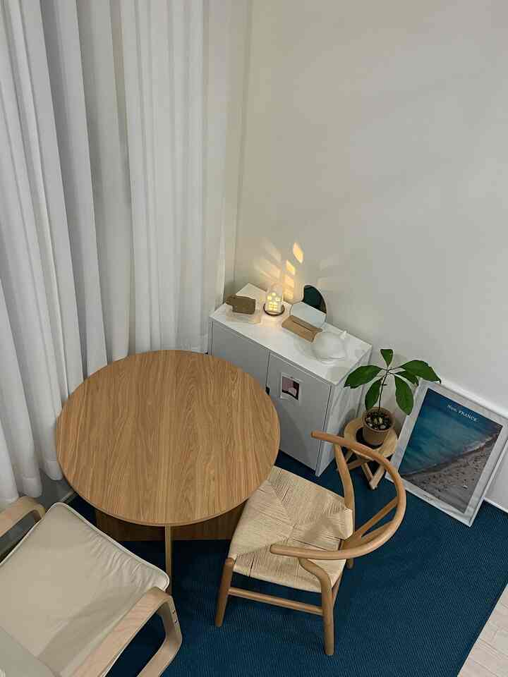 ネイビーのラグと木製のテーブル、アームチェアが配置されたミニマルで清潔感のあるリビング