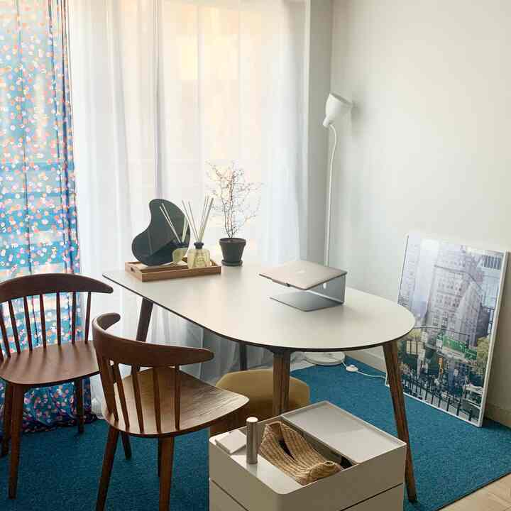 明るい白色の壁とテーブル、ブラウンの木製チェアが配置されたモダンなリビングルーム