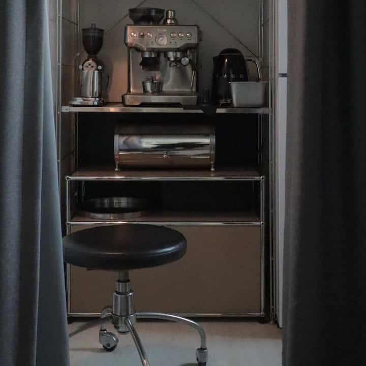Black and gray toned secondary kitchen home cafe featuring steel shelves and Breville coffee machine in a tidy space