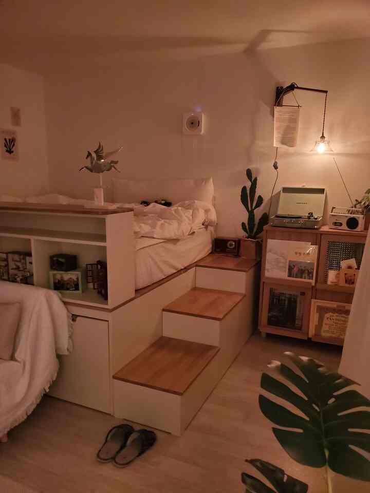 Natural-toned compact living room with white sofa and bed, wood tone dresser creating cozy atmosphere