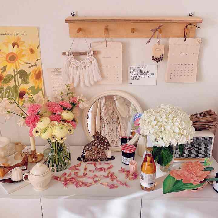 White and natural toned photo zone featuring vases with flowers and a round mirror, creating a relaxed natural atmosphere