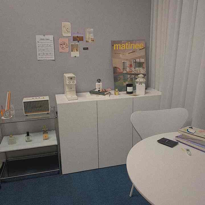 白と青のトーンの小さなリビングルーム、ダイニングテーブルと椅子、キャビネット、ポスターが配置されたミニマルなホームカフェ空間