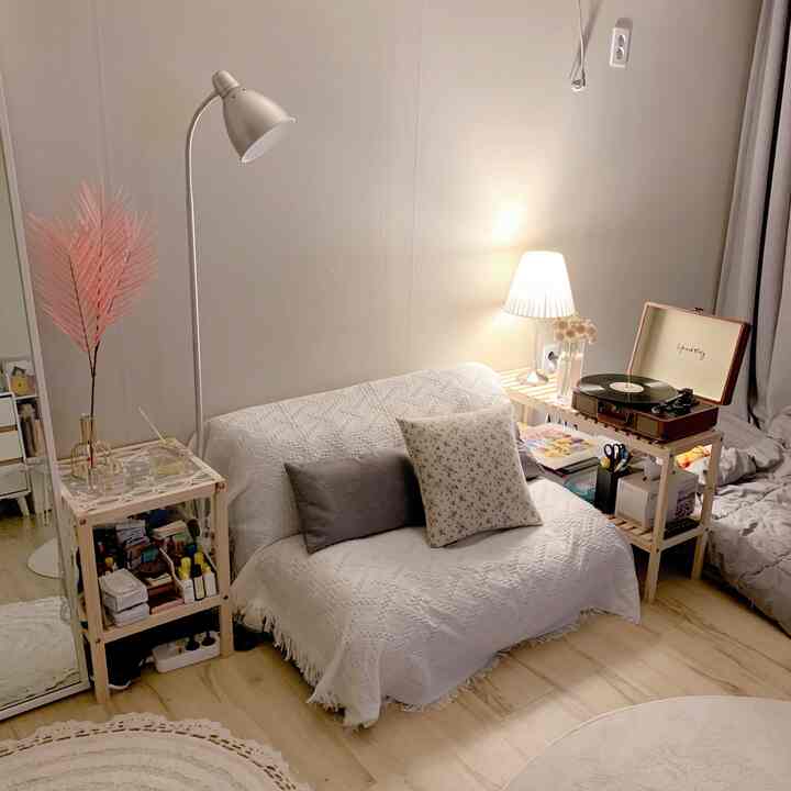 白と茶色のトーンのリビングルーム、コンパクトなソファとスタンドランプが配置された雰囲気のある空間