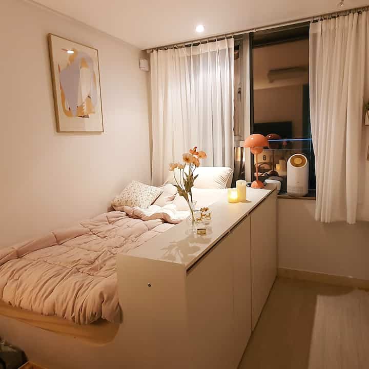 A cozy and warm 6-pyeong studio apartment in white and beige tones featuring a bed and storage cabinet