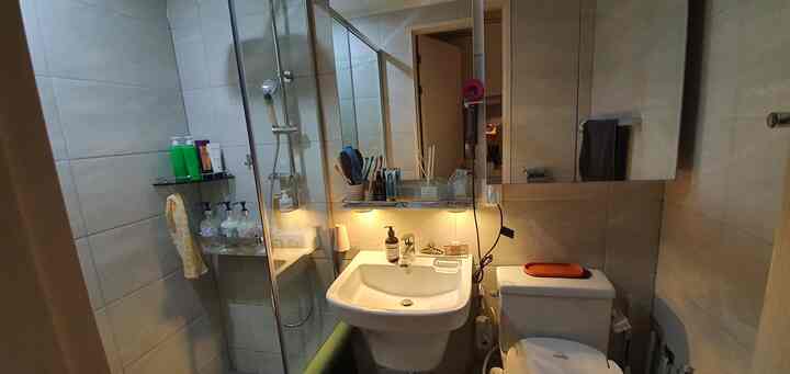 Beige-toned studio apartment restroom featuring a wash basin and toilet in a functional layout