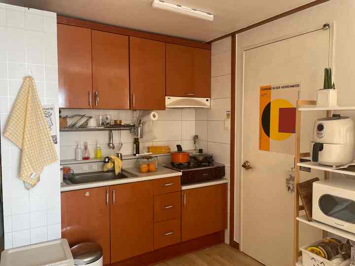 ブラウンのチェリーモールディングキッチン、黄色のポスターとオープンシェルフが配置されたヴィンテージ感のある空間