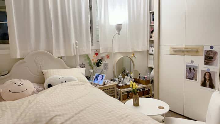 Cozy narrow bedroom in white and beige tones featuring bed and lighting elements