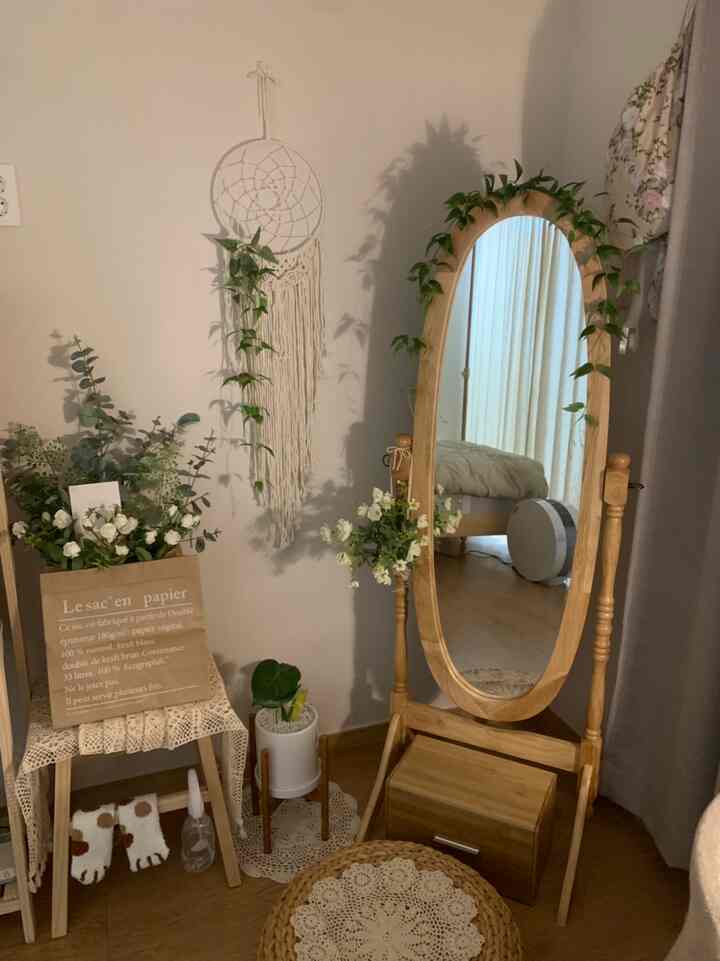 Cozy living room corner with natural wood tones and white background featuring a full-length mirror and plants in harmony