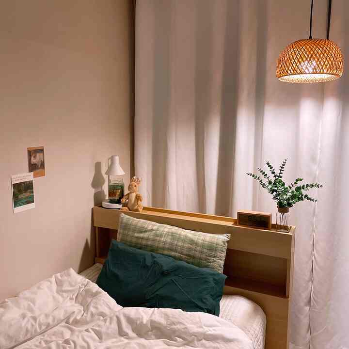 White and wood tone bedroom featuring rattan pendant light, curtains, and bedding creating a cozy atmosphere