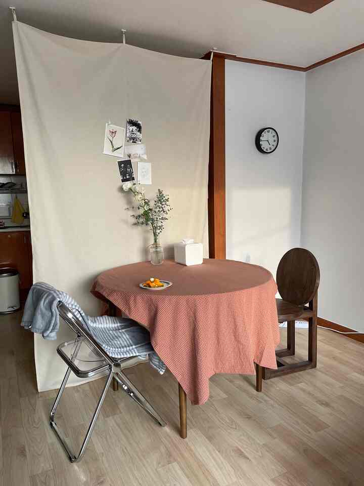 ナチュラルカラーと木製家具が調和するキッチン空間、赤いチェックのテーブルクロスの上に花瓶とおやつが置かれた温かみのある雰囲気のインテリア