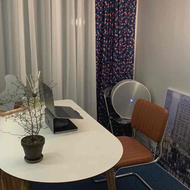 Blue and white toned living room featuring a white dining table, brown chair, and a plant pot creating a calm home office environment