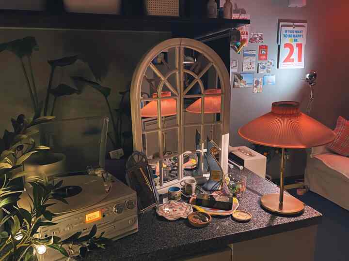 Cozy living room with pink table lamp, arched mirror, vintage turntable, and various decorative items