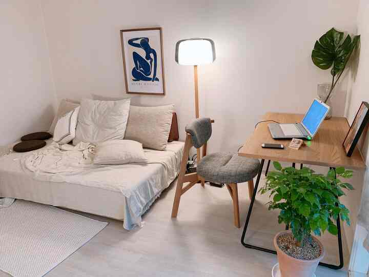 White and wood tone studio living room featuring a sofa bed and desk with natural cozy atmosphere