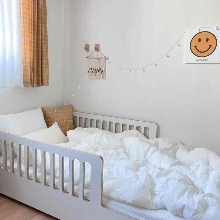 White and beige toned bedroom featuring a low bed and yellow checkered curtains, simple and cozy atmosphere