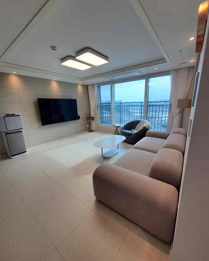 White and beige toned living room with large window, sofa, and coffee table creating a cozy modern atmosphere