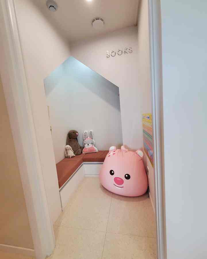 White and pink toned small kids' room corner with a pink bean bag and stuffed animal toys