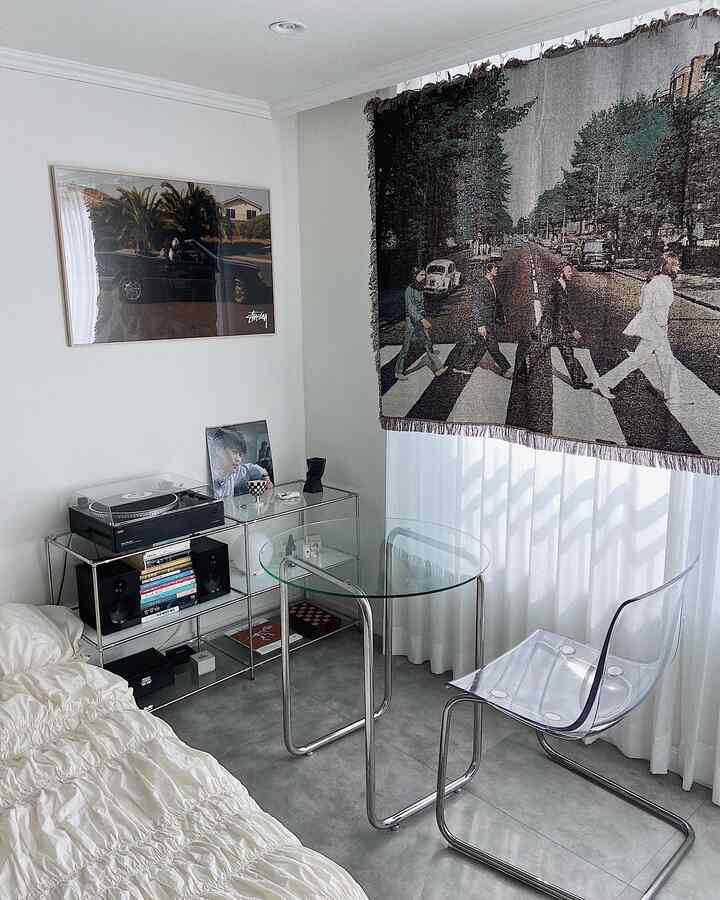 Modern bedroom in white and gray tones featuring a transparent chair and round glass table with a calm atmosphere